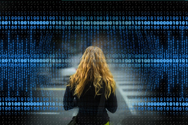 Žena stojí pred čiernym pozadím, na ktorom sú modré číselné dáta.jpg
